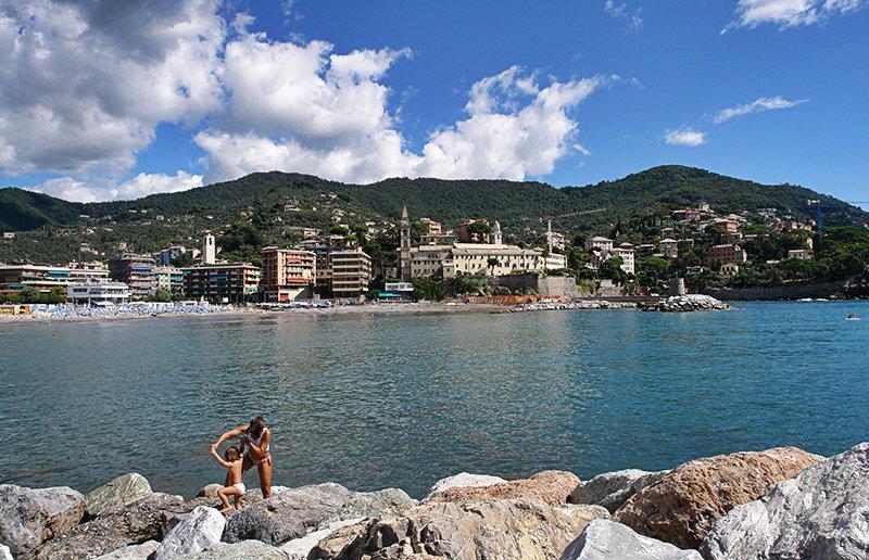 A family is playing on the rocks next to the sea in Recco